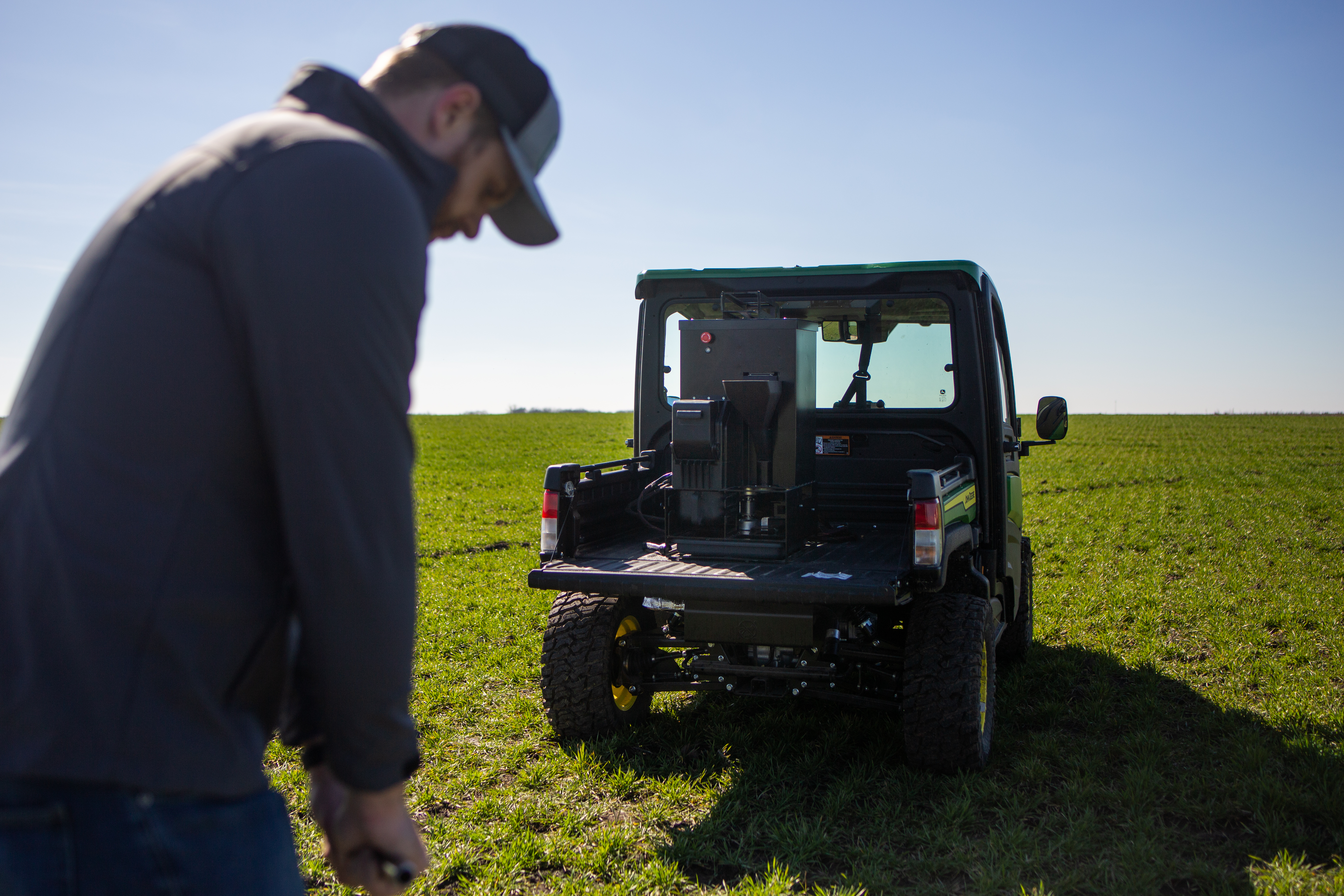 Image of a man taking soil samples on a field in front of a mini truck