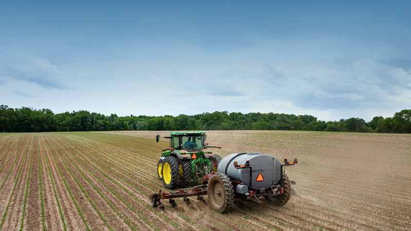 Tractor dragging a fertilizer on a field